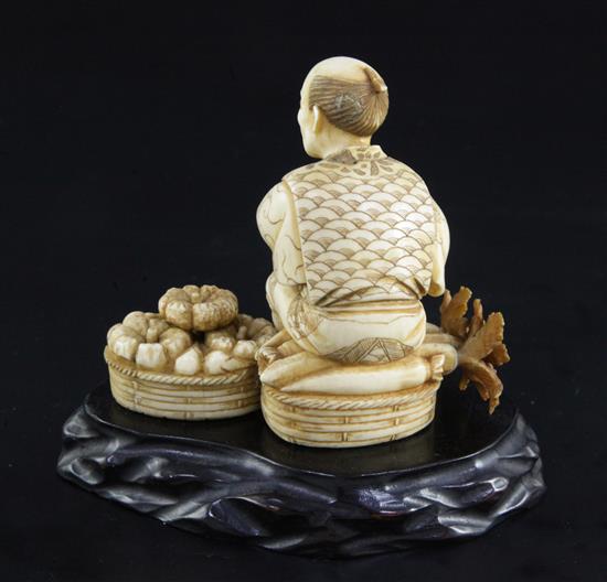 A Japanese ivory okimono of a farmer smoking a pipe, early 20th century, height 9cm, ebonised wood stand